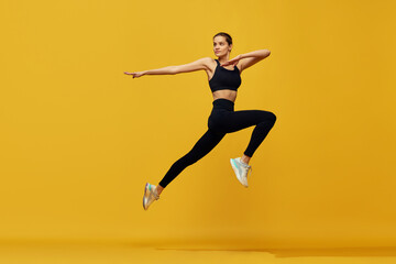 Fototapeta na wymiar Dynamic image of young beautiful girl in sportswear training, running against yellow studio background. Cardio session. Concept of sport, healthy and active lifestyle, beauty, fitness