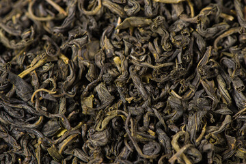 dry tea leaves in wooden spoon background.