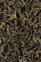 dry tea leaves in wooden spoon background.