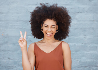 Black woman, portrait and tongue out with peace sign and afro against a gray wall background. Happy and goofy African female face smile showing peaceful hand emoji, sign and funny or silly expression - obrazy, fototapety, plakaty