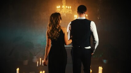 Two person sexy halloween couple walking man and blonde hair woman geddess in carnival mask back rear view. Gothic Girl lady Black dress. Portrait Guy fantasy prince Fashion model. dark party room 4k - Powered by Adobe