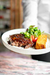 waiter hold in his hands ready beef steak ribeye meat