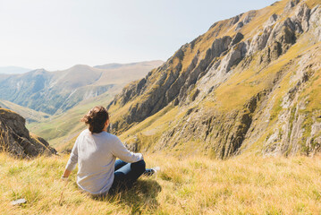 Naklejka na ściany i meble Chica sentada relajada en la montaña observando el paisaje 