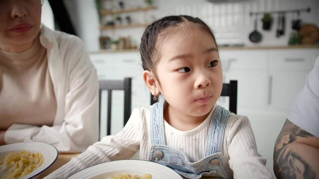 Asian Kid Eating Corn Flakes With Parents. Young family eating breakfast at home. Handheld Camera.