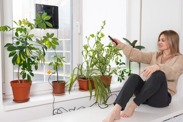 Woman cleaning windows at home with robotic cleaner.