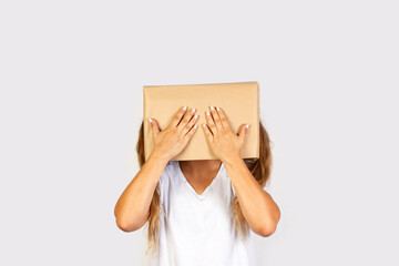 Mujer con caja de cartón en la cabeza y con un gesto de taparse los ojos con las manos sobre fondo gris liso y aislado. Vista de frente y de cerca. Copy space  - obrazy, fototapety, plakaty