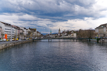 Obraz premium Scenic view of the old town of City of Zürich with Limmat River, quayside and footbridge on a cloudy spring day. Photo taken March 31st, 2023, Zurich, Switzerland.