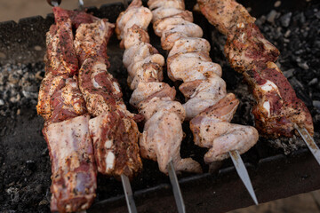 Pieces of meat and chicken wings are cooked on skewers