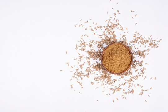 cumin seeds and cumin ground,powder. Pile of cumin powder isolated in a rock bowl on white background. Heap of ground caraway. Selective focus. Top view.
