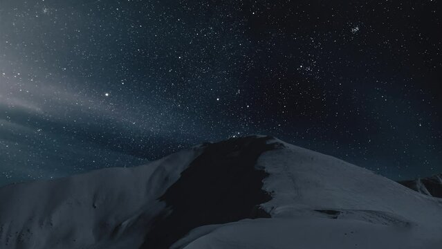 Dark starry night sky with stars over snowy winter mountains Astronomy Time lapse