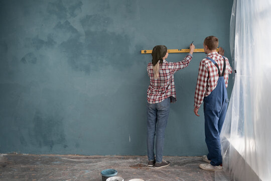 Repair home concept. A young couple are measuring a wall with spirit level.