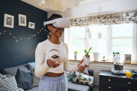 Teen girl smiling with Virtual Reality headset on, holding controllers - Powered by Adobe