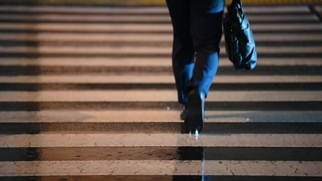 Walking step people on the crosswalk on a rainy lonely night. People are going back to their homes on a rainy night. Raindrops falling on a pedestrian crossing. Pedestrian crossing in a big city. Wet 