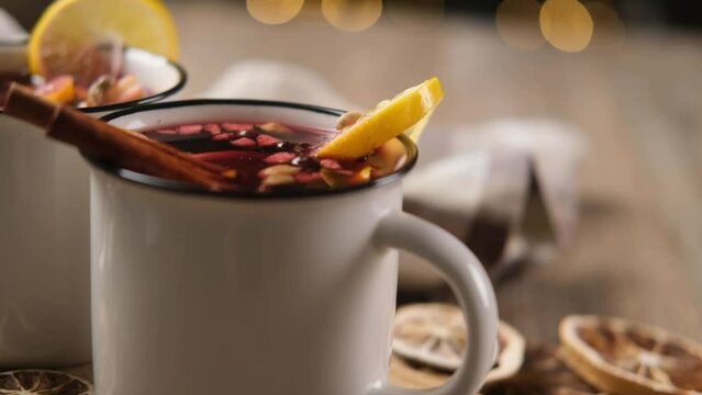 Aromatic red mulled wine in white steel mugs on wooden table