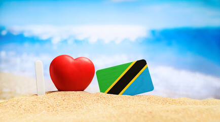 I love Tanzania and Zanzibar. Flag of Tanzania on the beach with a red heart. vacation and travel concept.