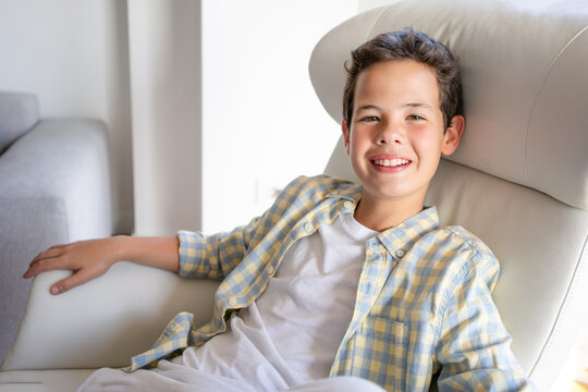 Portrait of smiling teenage boy sitting in sofa at home
