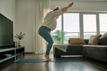 Woman doing online yoga at home. Female trener teaches asana in - obrazy, fototapety, plakaty
