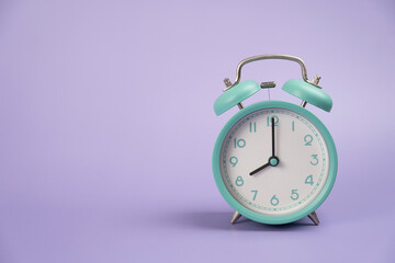 Retro alarm clock on purple table background, vintage style, flat lay