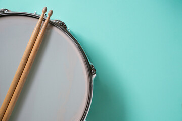Drum stick and drum on green table background, top view, music concept