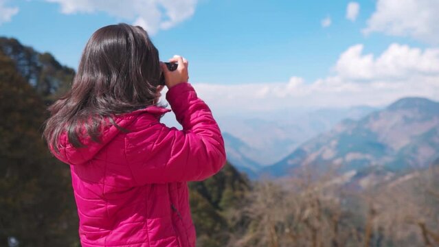 Teenager girl photographer taking photos of landscape while travelling. Beautiful young female photographer shooting with professional camera in Outdoor. Indian woman on summer travel adventure