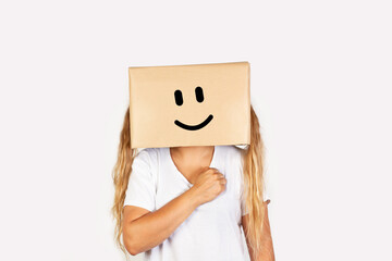 Mujer sonriente con una caja de cartón en la cabeza y con la mano en el corazón uuuuuun fondo blanco liso y aislado. Vista de frente y de cerca. Copy space - obrazy, fototapety, plakaty