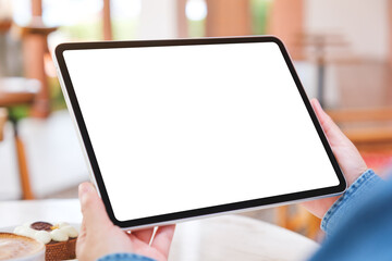 Mockup image of a woman holding digital tablet with blank white desktop screen with cake and coffee...