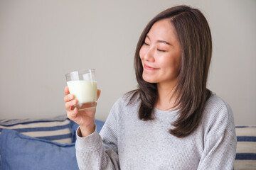 Portrait image of a young woman holding and drinking fresh milk