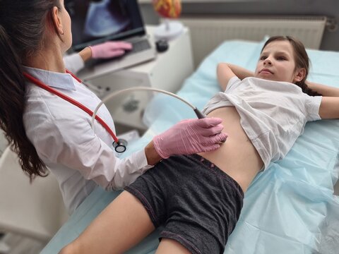 Doctor conducting ultrasound examination of internal organs of child in clinic