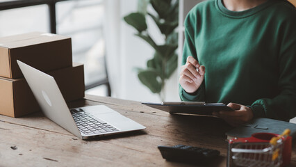 A person is using a laptop. Business owner opens an online store, she is checking orders from customers, sending goods through a courier company, concept of a opening an online business.