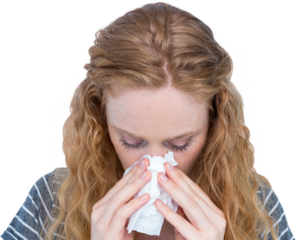 Close-up of woman blowing nose into tissue