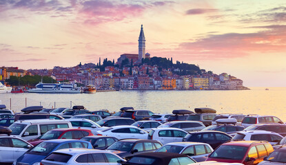 Rovinj Croatia. Sunrise sky above vintage town at Istria peninsula in Adriatic Sea. View from cars parking. Old Mediterranean architecture and buildings. Coastline tower of Church Saint Euphemia - obrazy, fototapety, plakaty