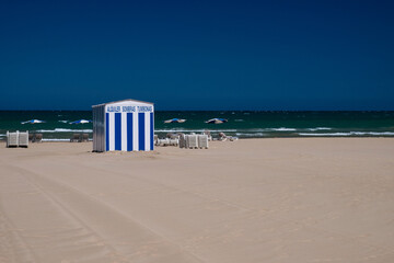 Umbrellas rental in the background of the sea. A rental tent with a sign in Spanish words 