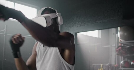 African American man with virtual glasses training in gym. Sportsman practicing punch with simulator program and a VR headset. Strong male using digital device. Concept of innovation technology. - Powered by Adobe