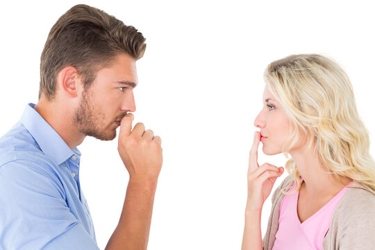 Young couple staying silent with fingers on lips