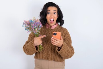 Portrait cute astonished young woman holds big bouquet of nice flowers over white background impressed unbelievable unexpected incredible notification advice