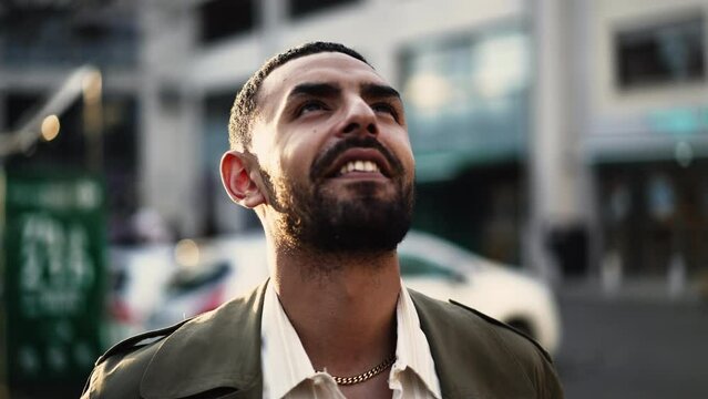 One Hopeful Arab man standing in street looking at sky in contemplation. Tracking shot, close-up face with happy expression