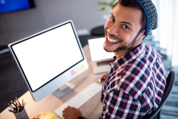 Portrait of man smiling while sitting by computer