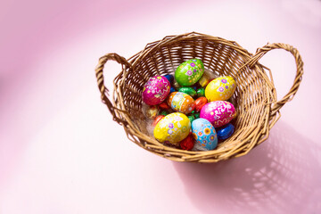 Fototapeta na wymiar Schokoladen Oster Eier in Korb auf pinkem Hintergrund 