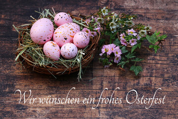 Grußkarte Frohe Ostern: Osternest mit rosafarbenene Ostereiern auf altem Holz und der Inschrift...