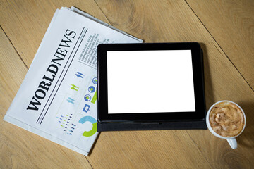 Digital tablet with coffee and newspaper on table
