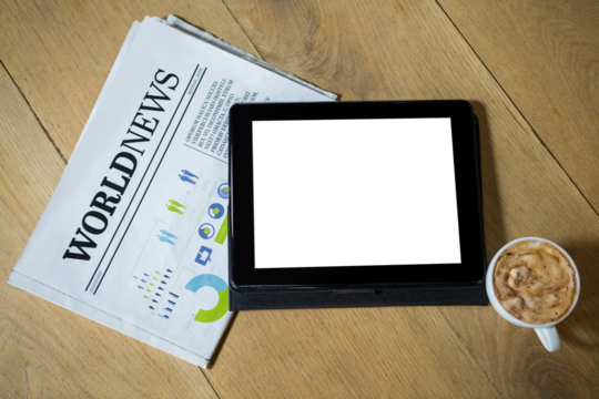 Digital tablet with coffee and newspaper on table