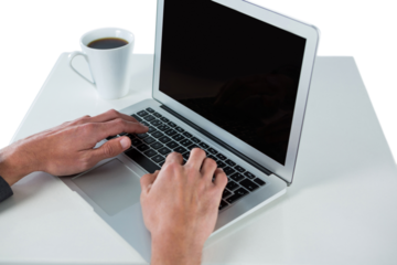 Cropped hands of businessman using laptop while having coffee