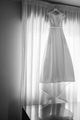 foto in bianco e nero di un abito da sposa appeso sopra una finestra