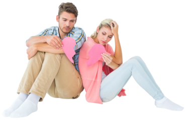 Attractive young couple sitting holding two halves of broken heart