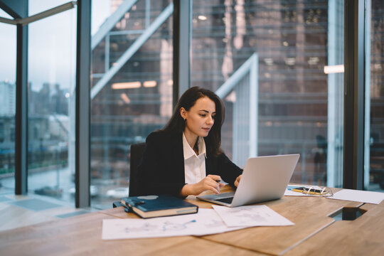 Focused businesswoman sitting at table and working on laptop in office