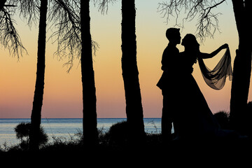 Fototapeta na wymiar bellissima coppia di sposi ripresa in silhouette al tramonto