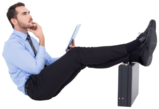 Businessman sitting with feet on his briefcase thinking 