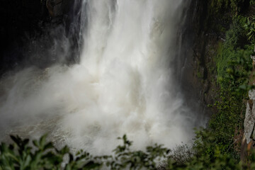 Fototapeta na wymiar A frothy white waterfall cascades over rocks into a pool below.