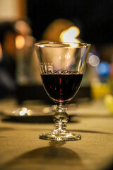 glass of wine on a table with candle lights in the background