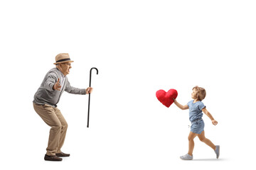 Little girl running to hug her grandfather and carrying a red heart